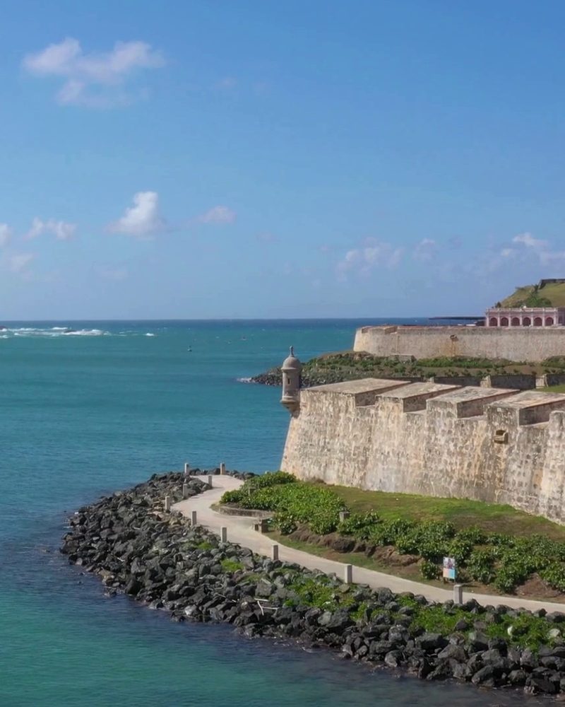 The sea walls and sentry box of Old San Juan meeting the turquoise Atlantic under a clear sky